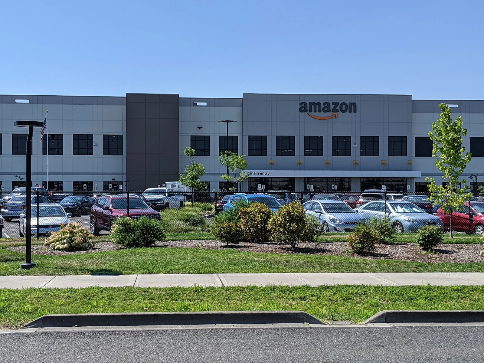Exterior of an Amazon fulfillment center in Troutdale, Oregon, with parked cars in front.